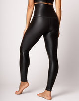 woman wearing high shine and sparkling jet black colored legging on grey background