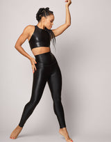 woman wearing high shine and sparkling jet black colored crop top and legging set on grey background