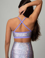 woman wearing sports bra with mermaid pattern of lavender purple colored sparkling fish scales on grey background