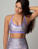 woman wearing sports bra with mermaid pattern of lavender purple colored sparkling fish scales on grey background