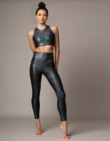 woman wearing sneaker length legging with mermaid pattern of midnight black colored sparkling fish scales on grey background