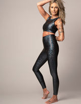 woman wearing crop top and legging set with mermaid pattern of midnight black colored sparkling fish scales on grey background