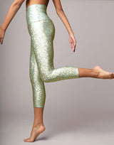 woman wearing legging with mermaid pattern of mint colored sparkling fish scales on grey background