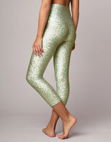 woman wearing legging with mermaid pattern of mint colored sparkling fish scales on grey background