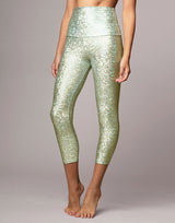 woman wearing legging with mermaid pattern of mint colored sparkling fish scales on grey background