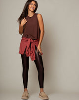 woman wearing chocolate brown colored tank and high shine, sparkling chocolate brown colored legging on grey background