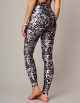 Person wearing black and white floral leggings on a neutral background