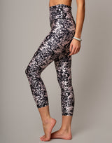 Person wearing black and white floral leggings on a gray background