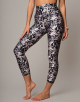 Person wearing black and white floral leggings on a gray background