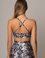 Person wearing a black and white floral sports bra and leggings on a neutral background
