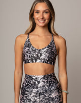 Woman wearing a black and white floral sports bra and leggings on a gray background