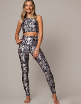 Woman wearing a black and white floral sports bra and leggings set on a gray background