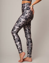 Person wearing black and white floral leggings on a gray background