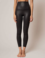 Person wearing black leggings on a plain background