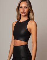 Woman wearing a black leather-like top against a neutral background
