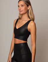 Woman wearing a black sports bra and leggings against a neutral background