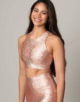 woman wearing crop top with mermaid pattern of peach colored sparkling fish scales on grey background