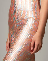 woman wearing legging with mermaid pattern of peach colored sparkling fish scales on grey background