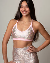 woman wearing sports bra with mermaid pattern of pink colored sparkling fish scales on grey background