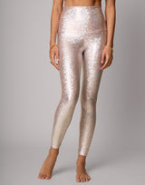 Person wearing sparkly silver leggings on a gray background