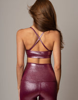 Person wearing a maroon sports bra and leggings set on a neutral background