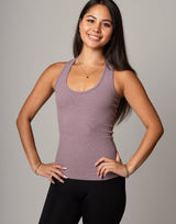 Woman wearing a mauve tank top and black leggings against a gray background