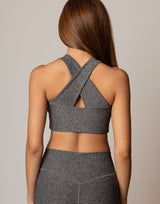 Person wearing a gray sports bra and leggings set on a neutral background