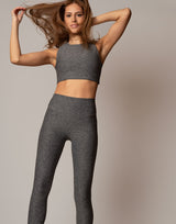 Woman wearing a gray athletic outfit against a plain background