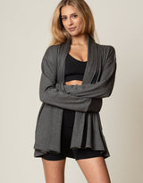 Woman wearing a gray cardigan over a black outfit on a beige background