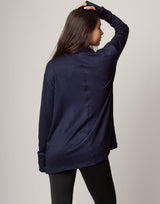 Woman wearing a navy blue cardigan over a red top on a gray background