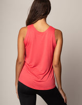 woman wearing tank in coral on grey background