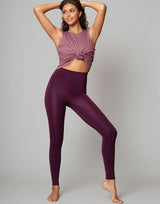woman wearing eggplant purple colored leggings on grey background