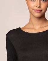 woman wearing long sleeve top in black on grey background