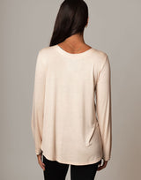 woman wearing ivory vanilla colored long sleeve top on grey background