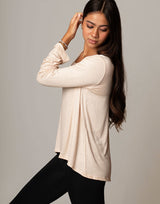 woman wearing ivory vanilla colored long sleeve top on grey background