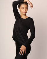woman wearing long sleeve top in black on grey background