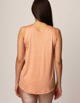 woman wearing peach colored tank on grey background