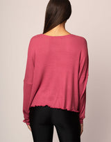 woman wearing oversized waffle knit long sleeve top in berry on grey background