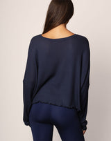 woman wearing oversized waffle knit long sleeve top in navy on grey background