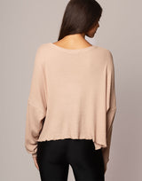 woman wearing oversized waffle knit long sleeve top in oatmeal beige on grey background