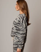 Woman wearing a camouflage outfit against a plain background