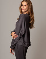 Woman wearing a dark gray outfit against a plain background