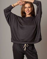 Woman wearing a dark gray oversized top and pants on a plain background