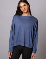 woman wearing denim blue colored pullover sweater on grey background