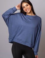 woman wearing denim blue colored pullover sweater on grey background