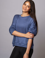 woman wearing denim blue colored pullover sweater on grey background