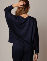 Person wearing a navy blue hoodie and pants against a plain background