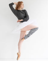 Dancer in a gray top and white skirt with striped stockings on a white background