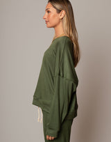 Woman wearing an olive green outfit against a plain background