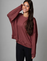 woman wearing relaxed and boxy reddish brown earthy colored pullover on grey background